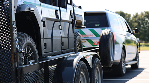trailer with damaged vehicle being pulled by an suv
